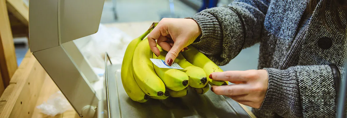 woman sticking label on banana after weighting