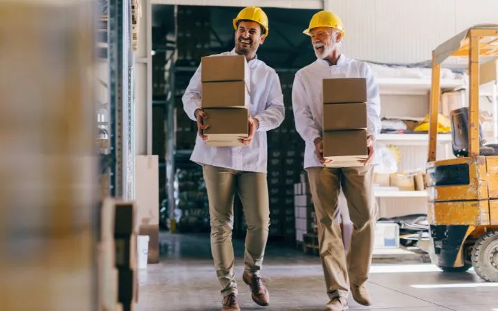 Deux hommes porten des boîtes dans l'entrepôt Zwei Männer tragen Faltschachteln in Lagerhalle