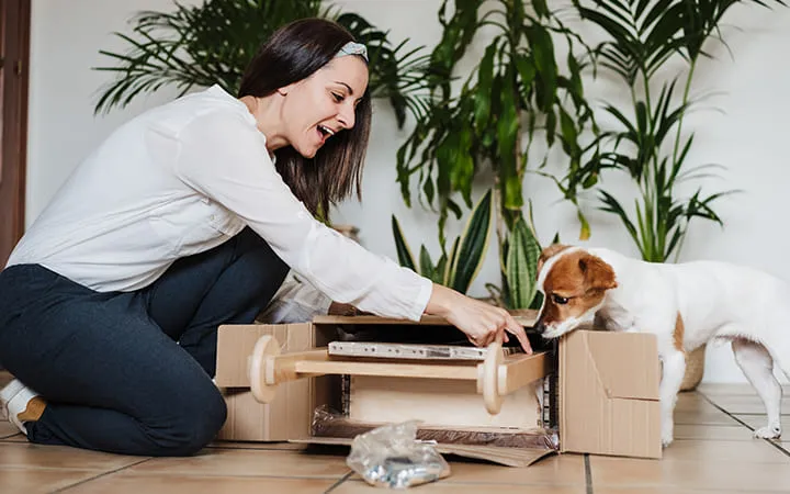 Karton wird ausgepackt von glücklicher Frau 
