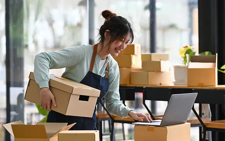 Frau Kennzeichnet Pakete und verpackt sie  Frau Kennzeichnet Pakete und verpackt sie