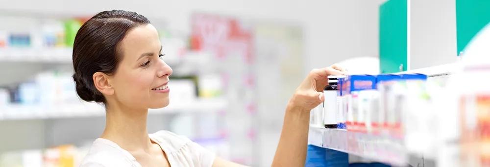 Frau liest in der Apotheke ein Etikett Frau liest in der Apotheke ein Etikett