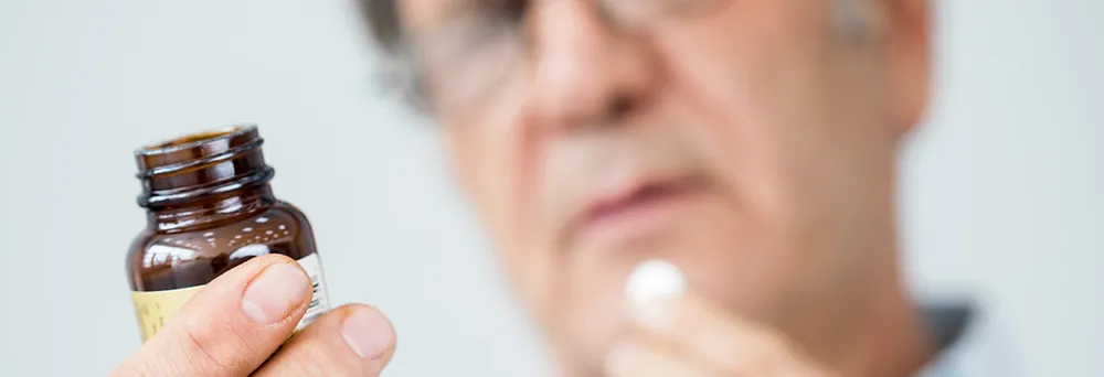 Mann liest Rückseite eines Medikaments Mann liest Rückseite eines Medikaments