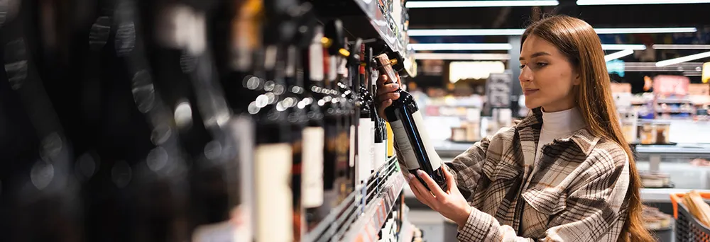 Wein kaufen im Supermarkt - Frau liest Etikett Wein kaufen im Supermarkt - Frau liest Etikett
