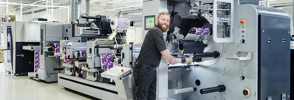 Produktionshalle von Labelprint24 - Mitarbeiter an Etikettenmaschine Produktionshalle von Labelprint24 - Mitarbeiter an Etikettenmaschine