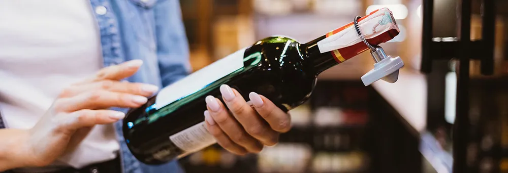 Frau liest Etikett einer Weinflasche 