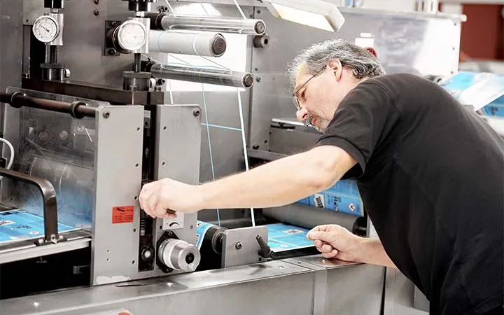 Person bestimmt Wickelrichtung der Etiketten an Maschine Person bestimmt Wickelrichtung der Etiketten an Maschine