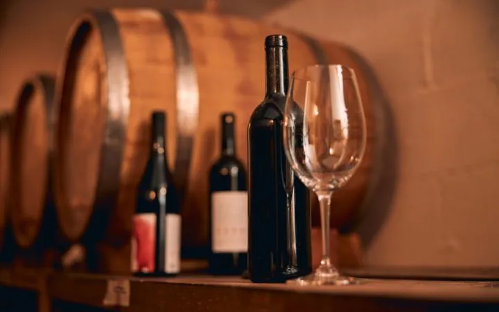 Weinflaschen und Weinglas auf einem Regal