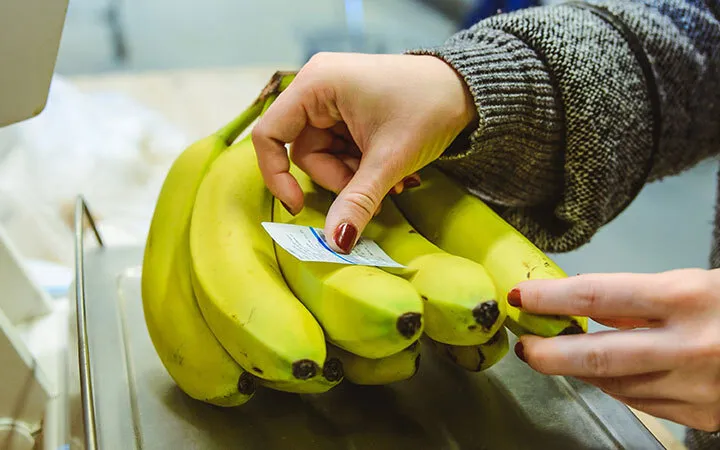 Bananen werden mit Etikett beklebt auf einer Waage Bananen werden mit Etikett beklebt auf einer Waage